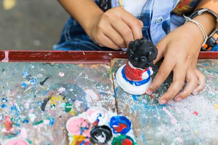 A child paints the colors of white plaster doll toys on the tableの写真素材
