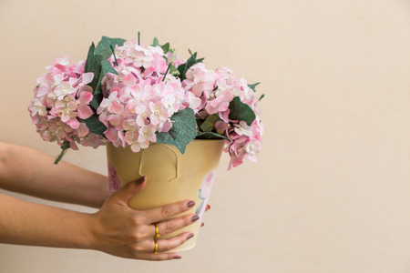 Hand hold buckets of fabric pink flowers on beige backgroundの写真素材