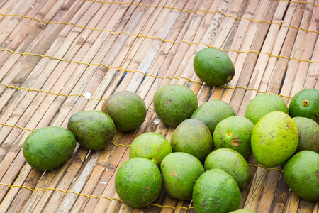 Fresh bunch of green Avocados on wooden net background