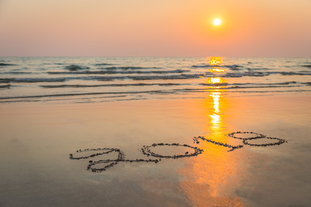 Numbers 2018 handwritten on sand at the beach during sunset time background