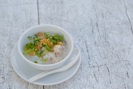 Boiled rice with pork in white bowl on white wood table backgroundの写真素材