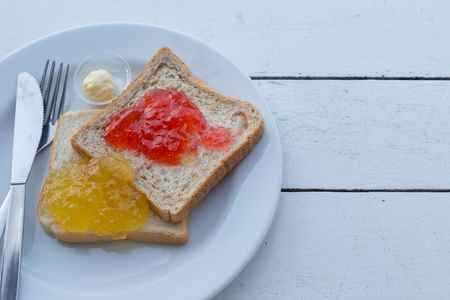 Strawberry and orange jam on the bread with white wood table baclgroundの写真素材