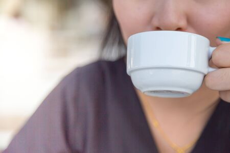 Woman drinking coffee in hand with blur baclgroundの写真素材