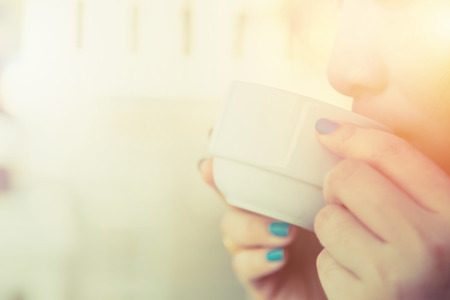 Woman drinking coffee in hand with blur baclground