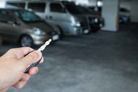 Hand holding car key remote at car park backgroundの写真素材