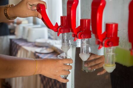 Hand turns on faucet of cold drinking water tank cooler