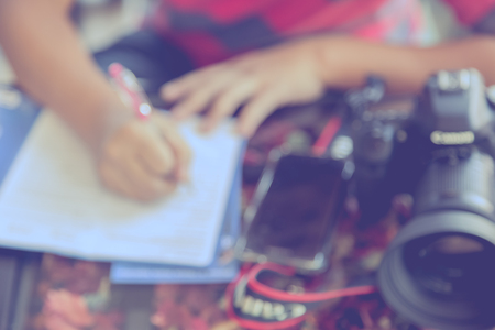 Blur image of man fill out application with camera and smart phone on the table backgroundの写真素材