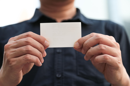 Confident male business executive with empty white business cardの写真素材