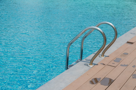 Stairs Ladder and handle down the swimming pool with blue water backgroundの写真素材