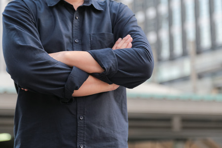 Confident male business executive  with arms crossed standing in front of office building backgroundの写真素材