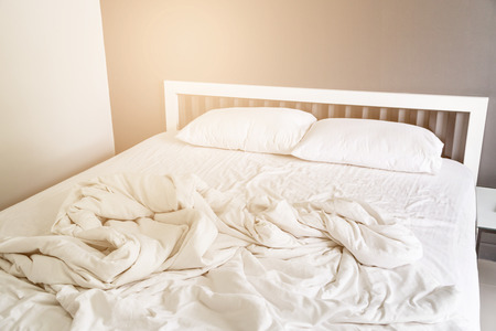 Two white pillow on bed and blanket with wrinkle messy in the bedroomの写真素材