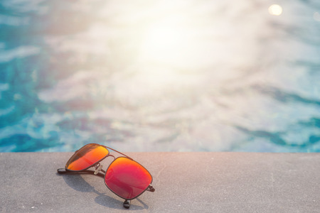 Fashion sun glasses near the swimming pool background
