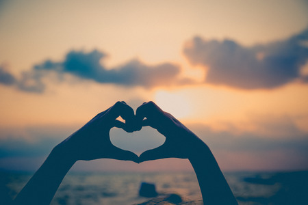 Hands make in heart form love with silhouette at sun set backgroundの写真素材