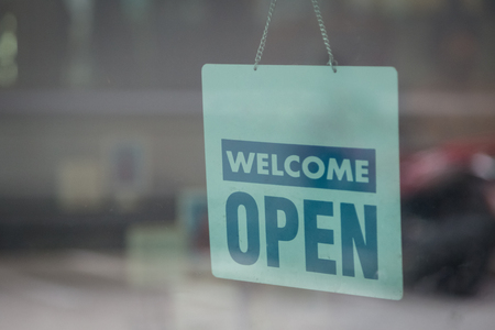 Open and welcome sign broad through the glass of window to let customers knowの写真素材