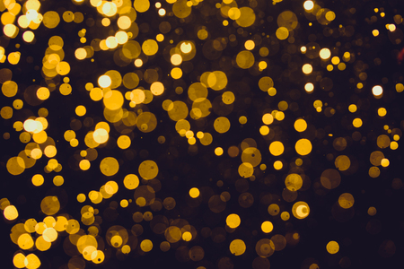 Abstract gold defocused bokeh of lights in dark backgroundの写真素材