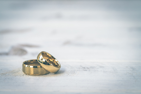 Golden rings, wedding rings of the bride and groom on white vintage wooden backgroundの写真素材