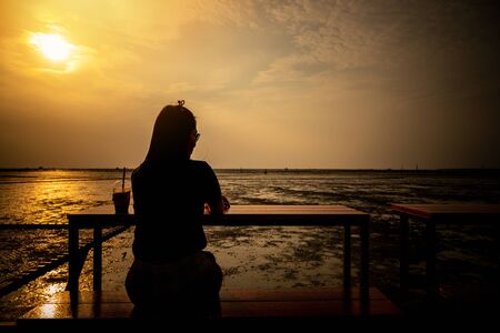 Women sitting and watching the sea at sunset nature backgroundの写真素材