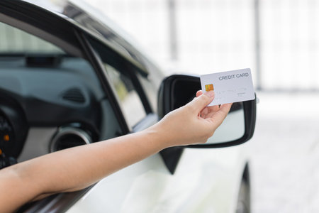 Closed up hand use credit card on car to pay for fuelの写真素材