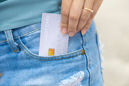 Closeup hand takes out generic of credit card in jeans trouser pocketの写真素材