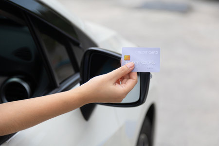 Closed up hand use credit card on car to pay for pay through the checkout checkpointの写真素材