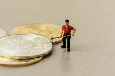Macro miner figures working on group of bitcoins with gray floor backgroundの写真素材