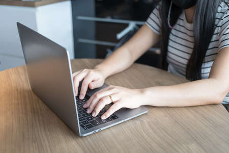 Working from home on laptop while typing chat to customer communicates on internet in home office,...