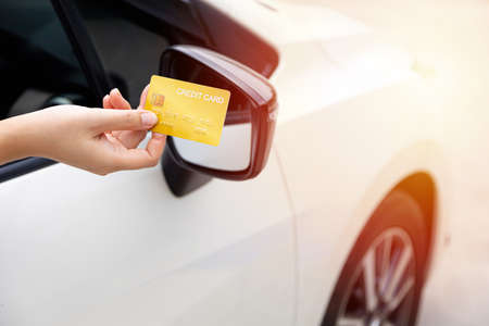 Closed up hand use credit card on car to pay for pay through the checkout checkpoint