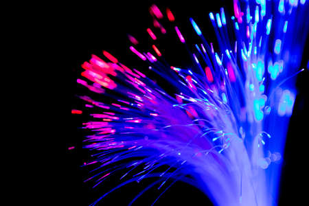 Close up of blurred light fiber optics for communication technology network on black backgroundの写真素材