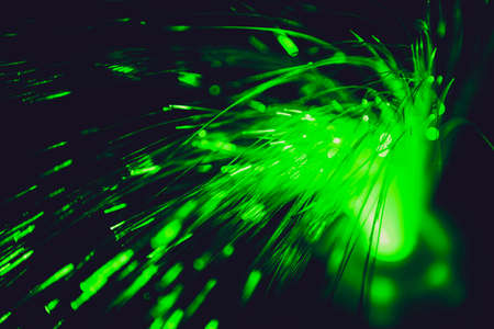 Close up of blurred green light fiber optics for communication technology network on black backgroundの写真素材