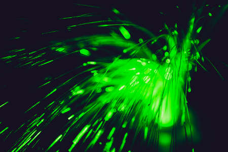 Close up of blurred green light fiber optics for communication technology network on black backgroundの写真素材
