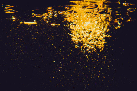 Gold bokeh from water of lights on black backgroundの写真素材