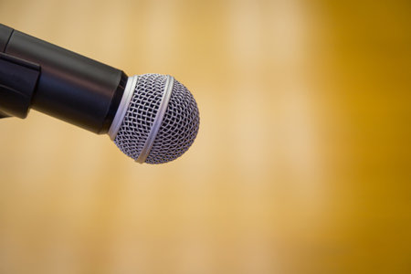 Close up of microphone on a podium in an auditorium with gold backgroundの写真素材