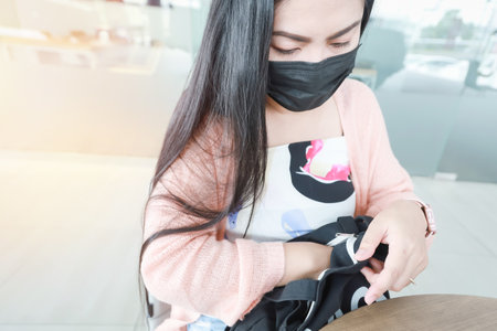 Asian woman sits on a smartphone at a car showroom while waiting for the mileage check to completeの写真素材