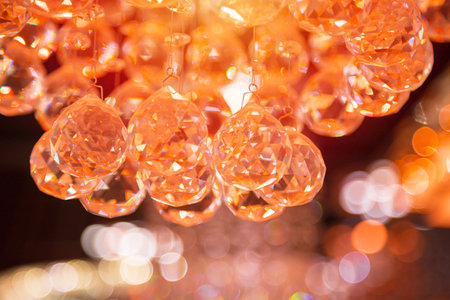 Beautiful crystal chandeliers warm light reflecting through brushed czech glass crystals hanging on vintage chandelier with bokeh backgroundの写真素材