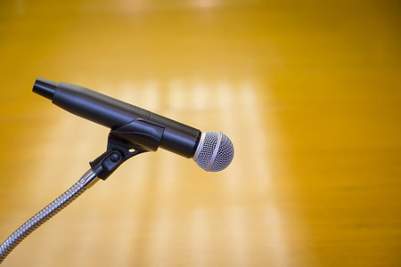 Close up of microphone on a podium in an auditorium with gold backgroundの写真素材