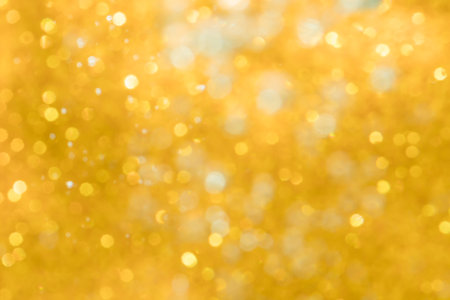 Golden abstract sparkles or glitter lights Defocused circles bokeh backgroundの写真素材