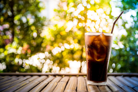 Beverage glass with ice cubes on bamboo table and bokeh backgroundの写真素材