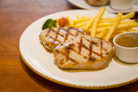 Grilled Pork Steak Served with French Fries and Vegetablesの写真素材