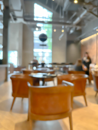 A blurred image of a modern coffee shop, elegantly decorated and warm, with customers happily working and chatting.の写真素材