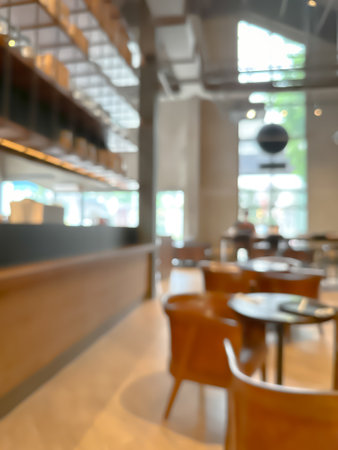 A blurred image of a modern coffee shop, elegantly decorated and warm, with customers happily working and chatting.の写真素材
