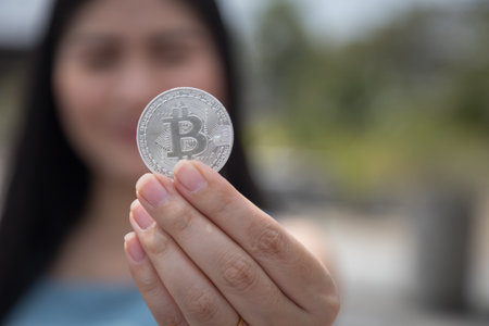 Smiling beautiful Female holding Bitcoin digital currency and cryptocurrency with blur background. Concept of Cashless Society web virtual money mining.の写真素材