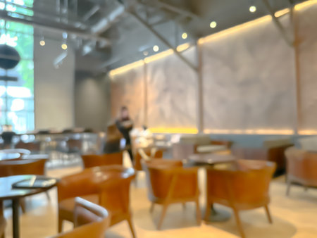 A blurred image of a modern coffee shop, elegantly decorated and warm, with customers happily working and chatting.の写真素材