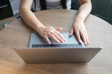 Working from home on laptop while typing chat to customer communicates on internet in home office,...