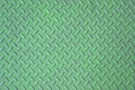 Green diamond plate metal surface with visible wear and scratchesの写真素材