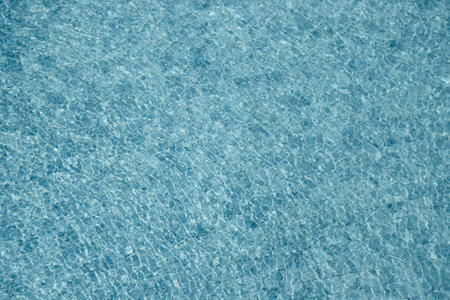 Vibrant blue water surface with shimmering reflections and ripples under sunlight.の写真素材