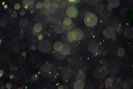 Defocused bokeh lights of different sizes and colors on a dark background.の写真素材