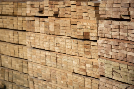 Stacked wooden planks in a lumberyard, various shades and textures, neatly arranged.