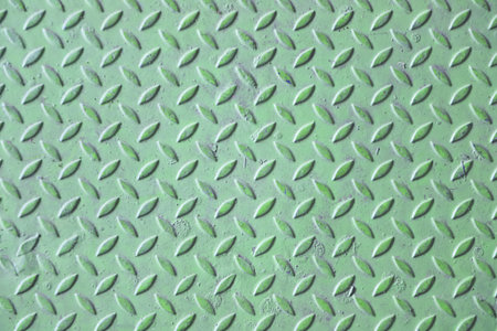 Green diamond plate metal surface with visible wear and scratchesの写真素材