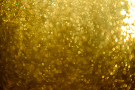 Abstract blurred golden glitter texture with sparkling bokeh lights creating a festive background.の写真素材