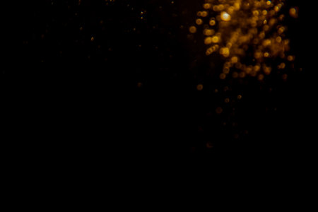Abstract blurred golden bokeh lights against a dark background creating a dramatic and festive atmosphere.の写真素材